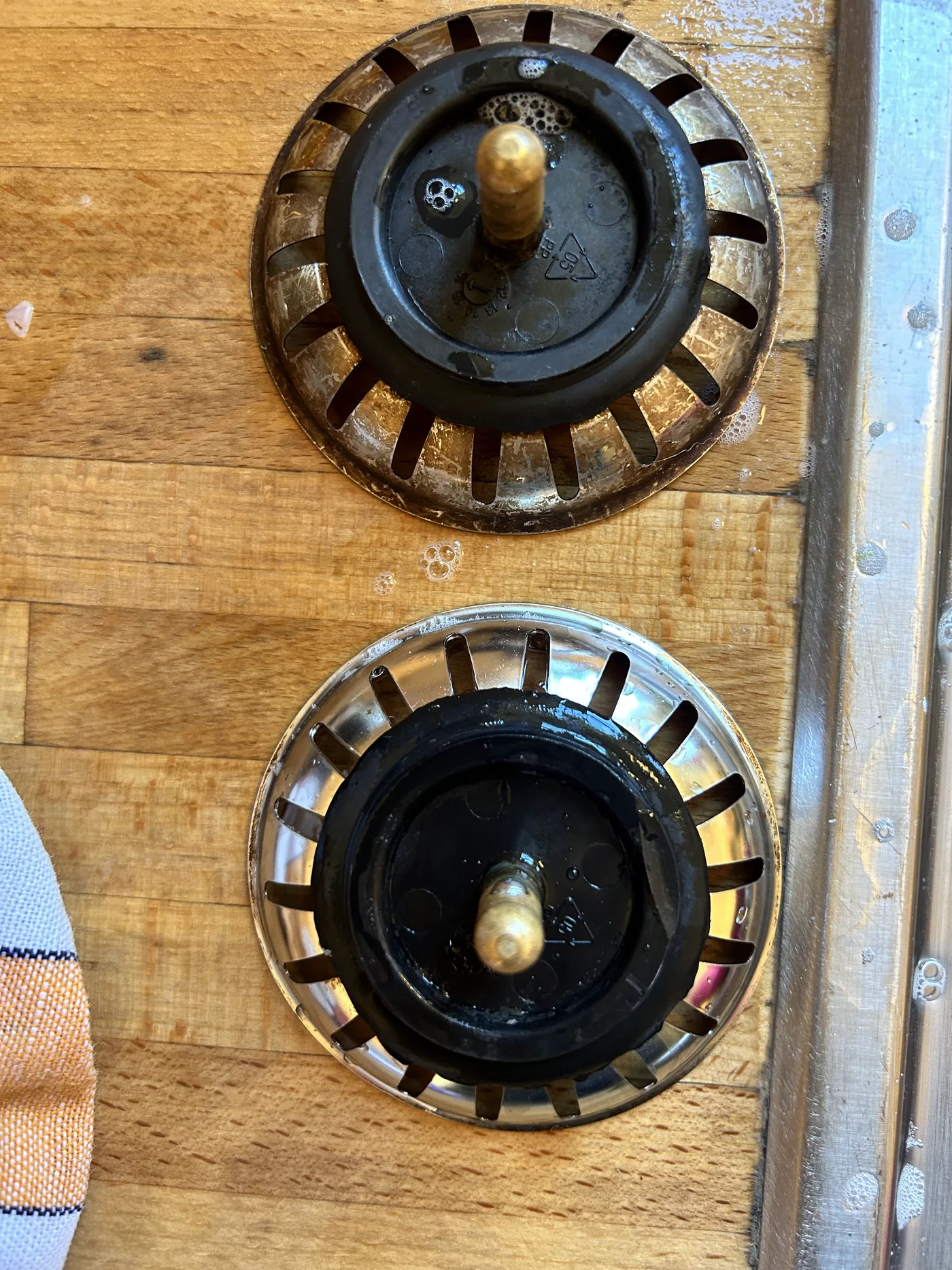 Deux crépines d'évier en inox sur un comptoir de bois, avant et après nettoyage