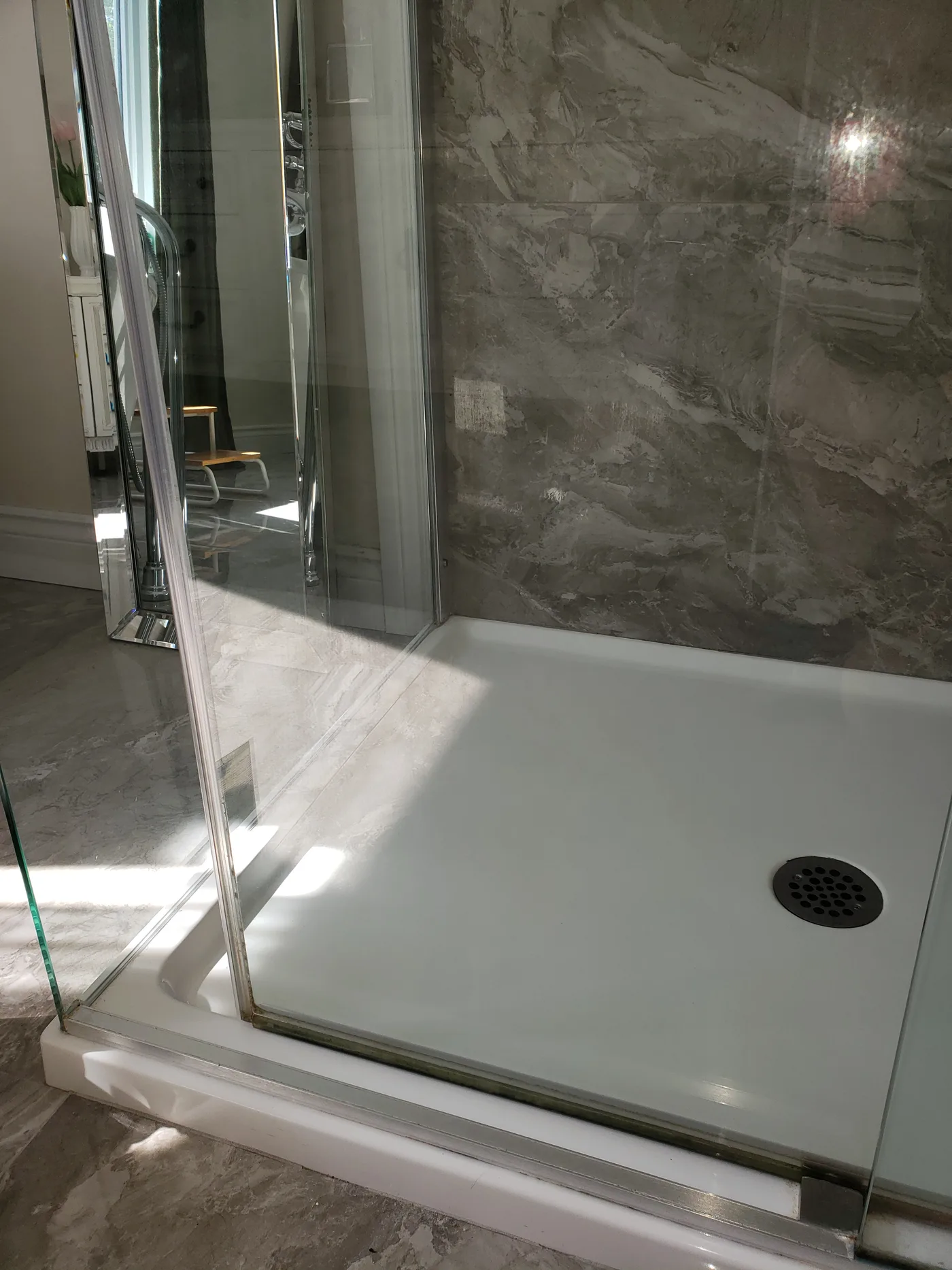 Douche vitrée aux parois de marbre et base impeccable après nettoyage